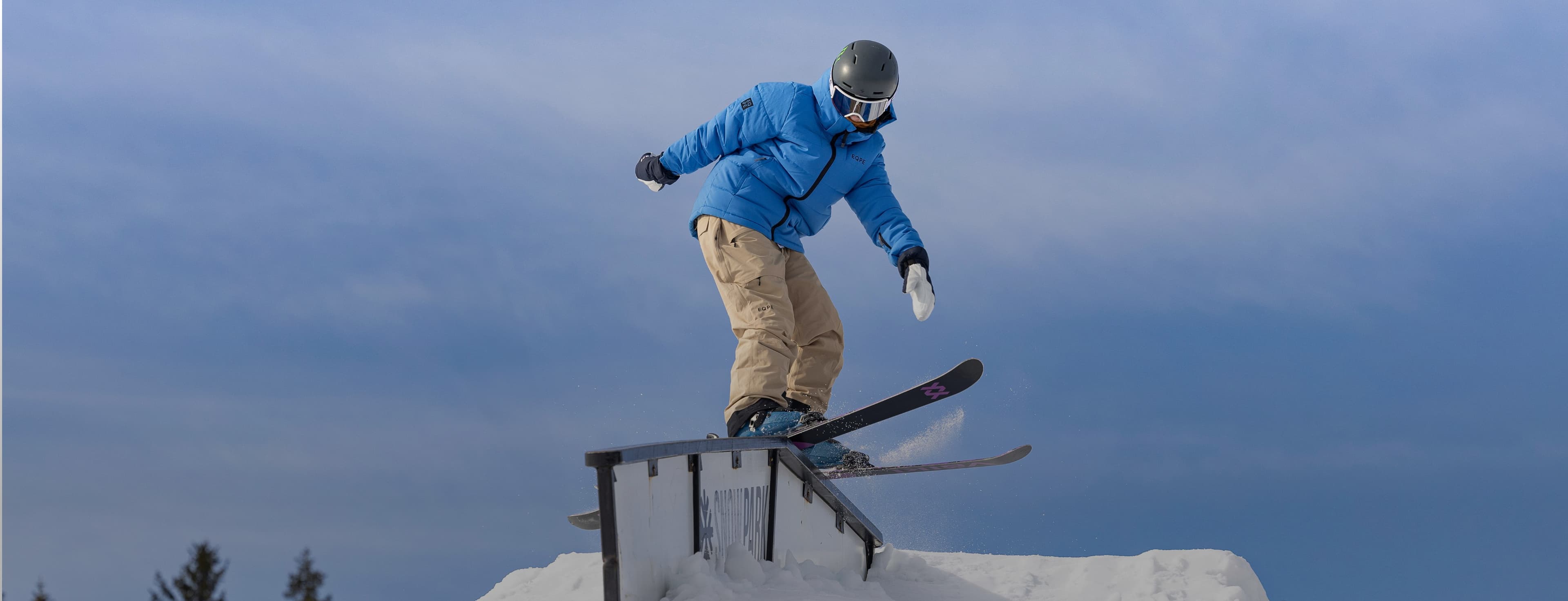 Kid sliding along a metal rail on skis.